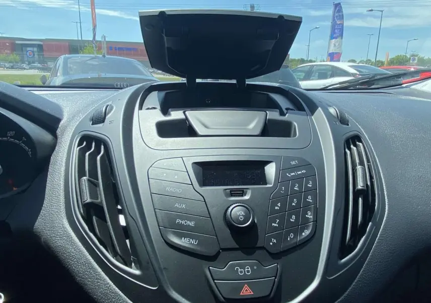 Vue rapprochée du tableau de bord noir du Ford Tourneo Courier 2022 avec commandes radio et rangement ouvert.