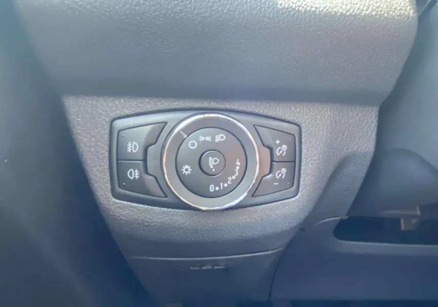 Gros plan sur le bouton de réglage des phares du Ford Tourneo Courier 2022, intérieur noir texturé.