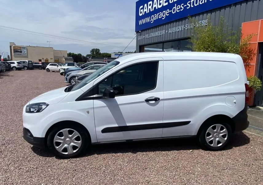 Fourgon blanc Ford Tourneo Courier 2022 vu de profil côté gauche, avec porte latérale coulissante et enjoliveurs cache moyeu.