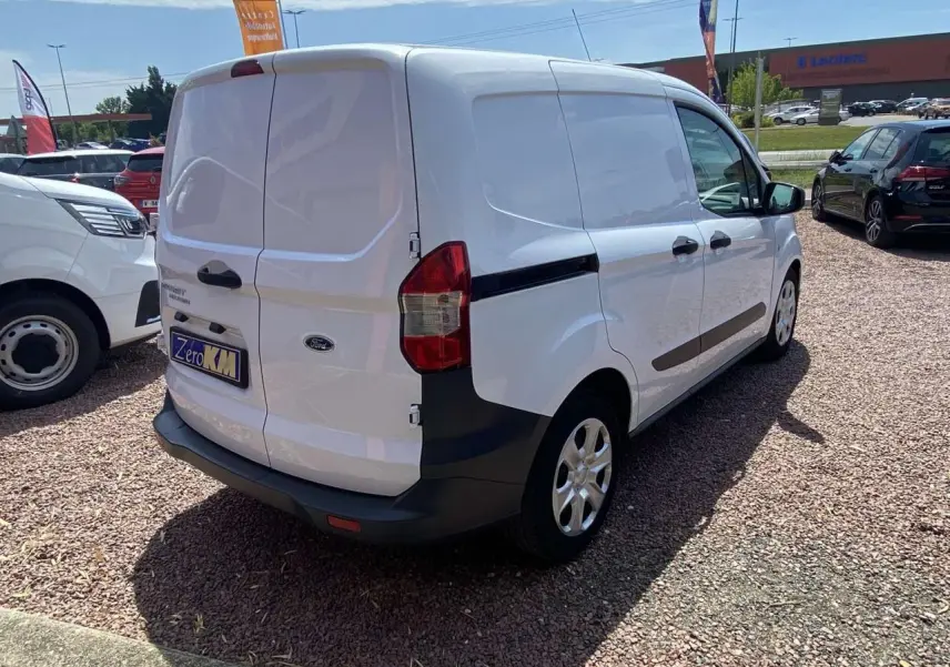 Vue 3/4 arrière droite d’un Ford Tourneo Courier blanc 2022 avec portes arrière battantes tôlées et porte latérale coulissante.