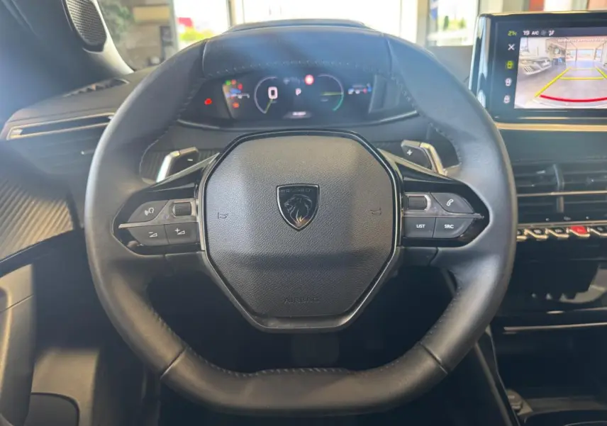 Vue intérieure centrée sur le volant cuir du Peugeot 2008 Hybrid 145 Allure avec cockpit numérique et écran tactile.