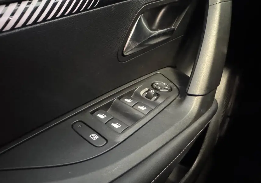Gros plan sur la commande des vitres électriques côté gauche de la porte intérieure noire du Peugeot 2008 Hybrid 145 e-DCS6 Allure.