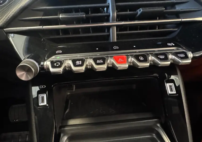 Vue rapprochée du tableau de bord du Peugeot 2008 Hybrid 145 Allure, montrant les commandes de climatisation et les ports USB.