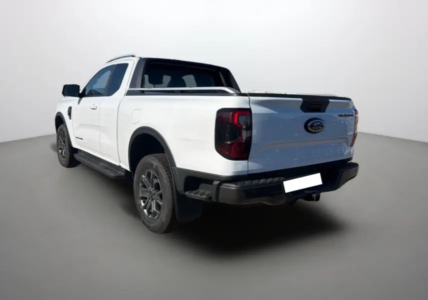Ford Ranger 2.0 205 Wildtrak Supercab blanc pur vu en 3/4 arrière droit avec attelage et barres de toit.
