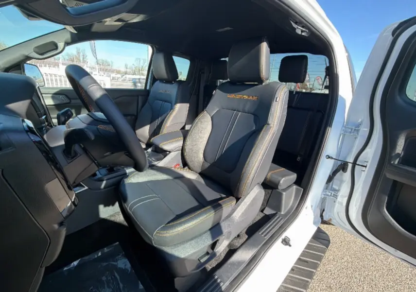 Intérieur du Ford Ranger Wildtrak 2025 blanc, vue côté gauche sur les sièges avant en cuir noir avec surpiqûres orange.