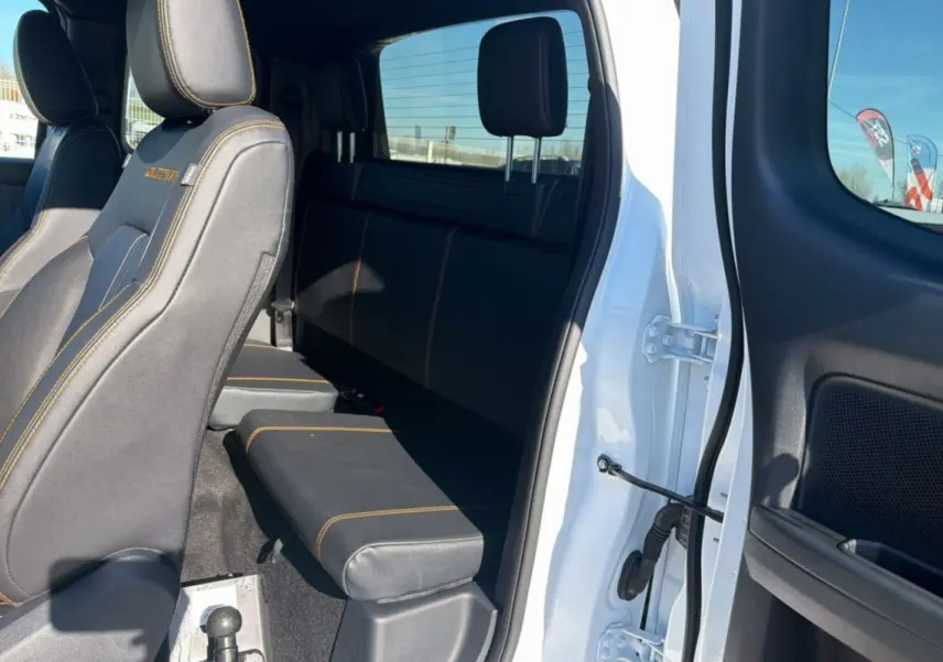 Vue intérieure côté droit du Ford Ranger blanc 2025, montrant les sièges arrière et avant avec surpiqûres orange.