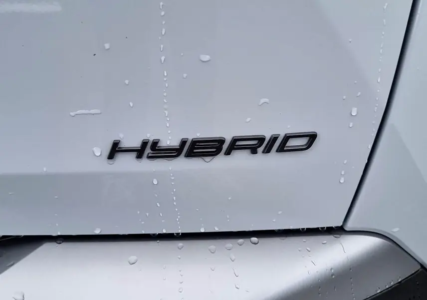 Gros plan sur l’inscription « Hybrid » noire sur la partie arrière blanche d’un Peugeot 3008 toit noir.