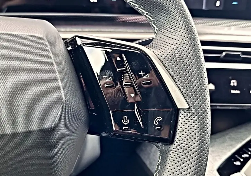 Gros plan sur les commandes multifonctions noires à gauche du volant cuir perforé du Peugeot 3008 blanc toit noir.