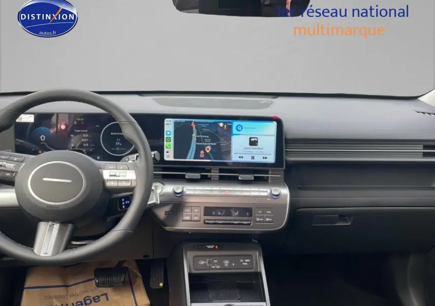 Vue intérieure du tableau de bord du Hyundai Kona 2025 avec écran tactile central affichant la navigation et le volant multifonction en cuir noir.