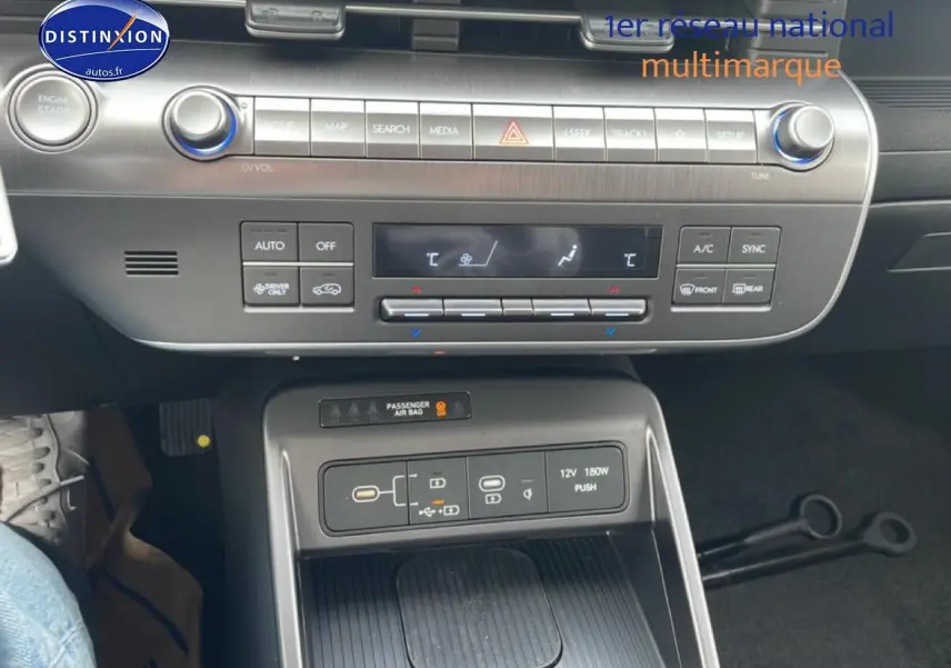 Vue rapprochée de la console centrale du Hyundai Kona 2025 bleu, montrant les commandes clim et recharge sans fil.