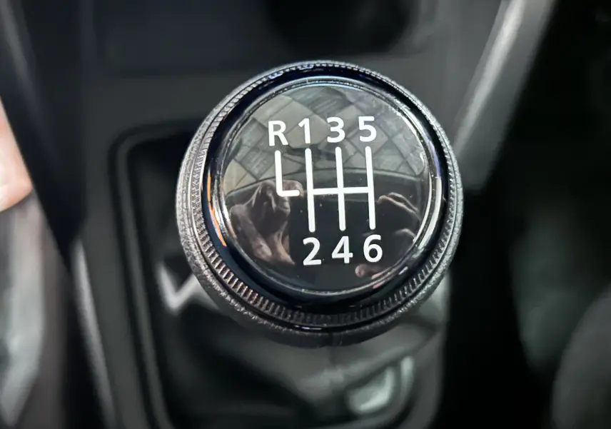 Gros plan sur le levier de vitesses manuel noir du Dacia Duster BluedCi 115, affichant les six rapports et la marche arrière.