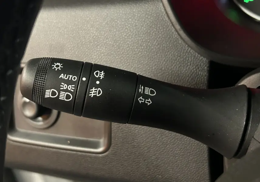 Gros plan sur la commande des phares et clignotants du Dacia Duster 2023, intérieur noir texturé.