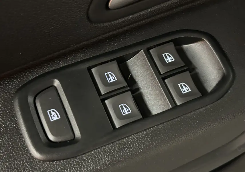Gros plan sur les commandes électriques des vitres côté conducteur du Dacia Duster blanc, version 2023.