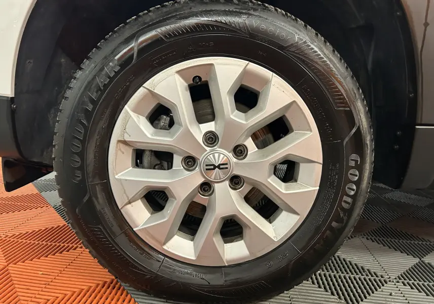 Gros plan sur la roue avant gauche du Dacia Duster blanc 2023 avec jante alliage et pneu Goodyear.