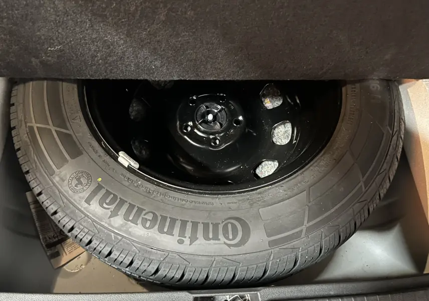 Gros plan sur la roue de secours Continental dans le coffre d’un Dacia Duster blanc 2023.