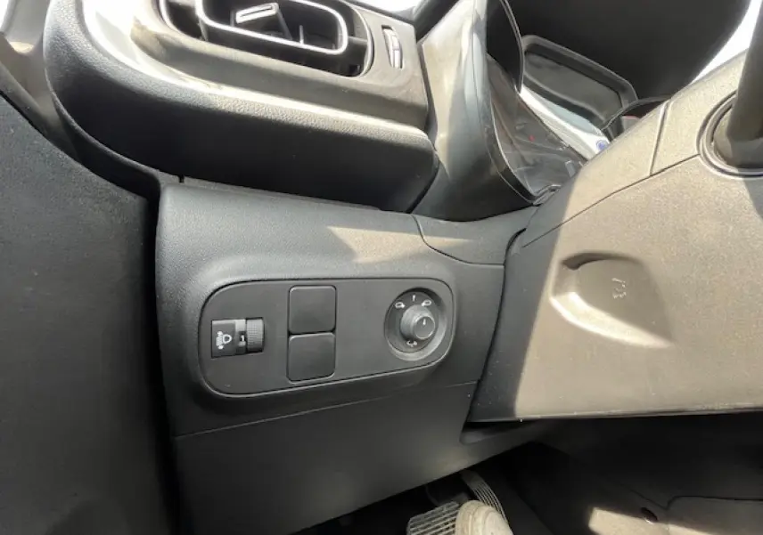Vue intérieure côté gauche du tableau de bord noir de la Citroën C3 2023, avec commandes des rétroviseurs et éclairage.