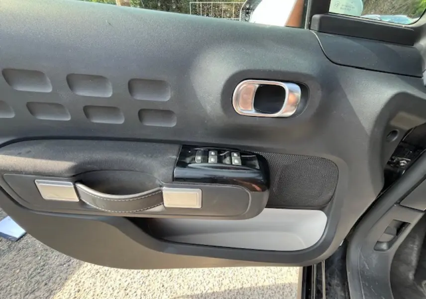 Vue rapprochée de la porte avant gauche noire de la Citroën C3 2023, avec commandes de vitres et poignée design.