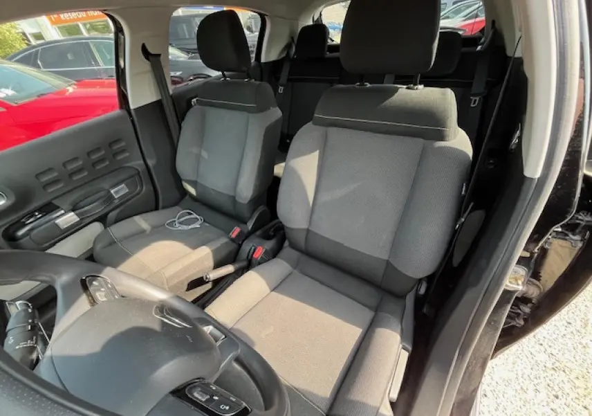 Vue intérieure côté conducteur de la Citroën C3 noire 2023, montrant les sièges tissu gris et le volant multifonction.