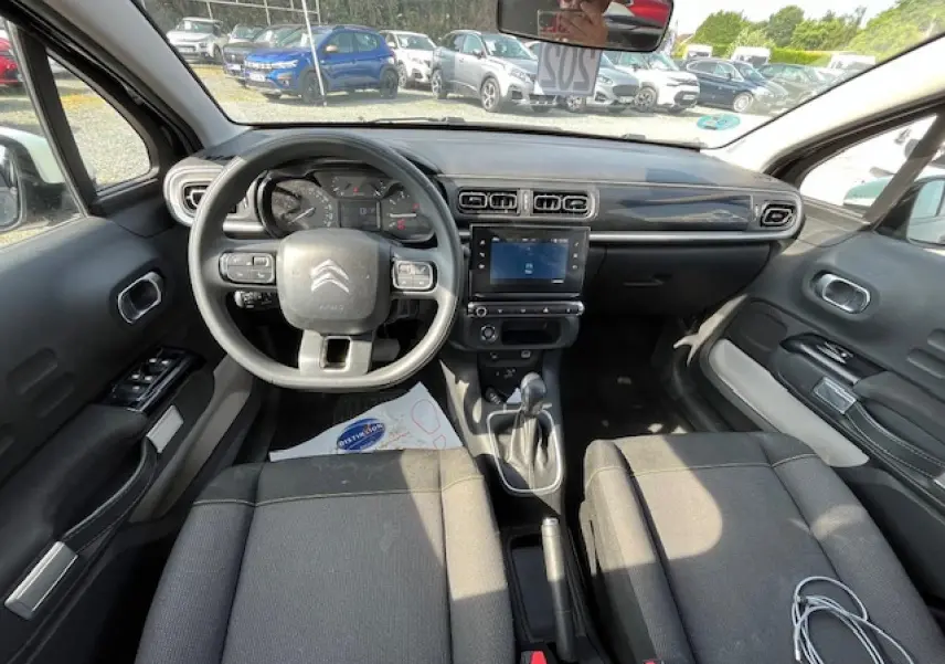 Vue intérieure avant de la Citroën C3 noire 2023, montrant le tableau de bord avec écran tactile et volant multifonction.