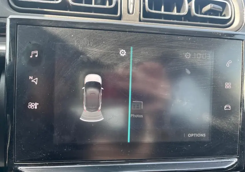 Écran tactile intérieur montrant l'aide au stationnement avec vue aérienne d'une Citroën C3 noire.