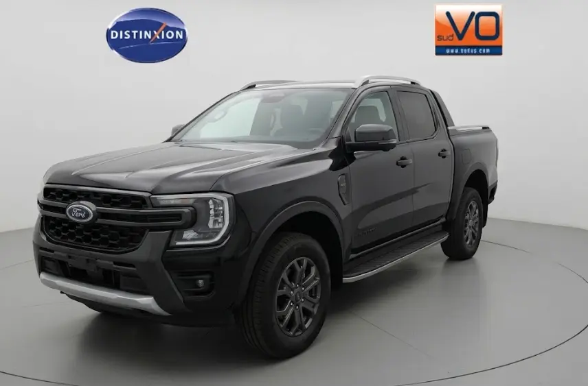 Ford Ranger Wildtrak noir vu en 3/4 avant droit, avec barres de toit, marchepieds et jantes alliage 18 pouces.