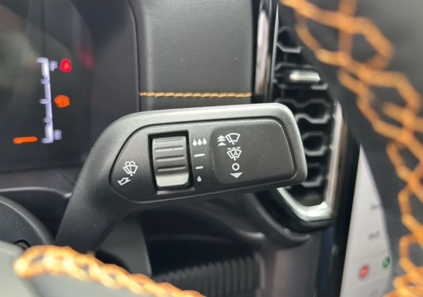 Gros plan sur la commande des essuie-glaces du Ford Ranger Wildtrak 2026, volant cuir noir avec surpiqûres orange.