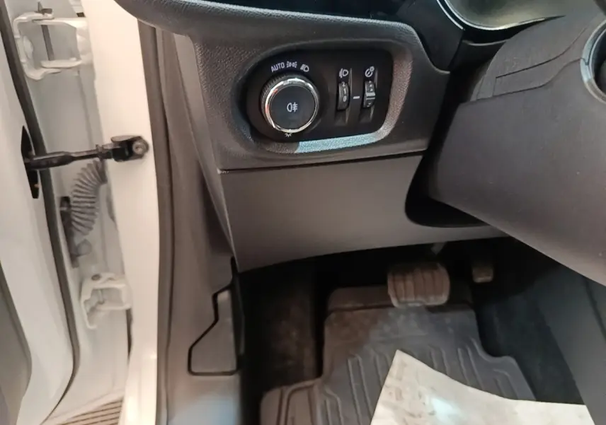 Détail intérieur côté gauche d'une Opel Corsa blanche 2022, avec commandes d'éclairage et pédale visible.