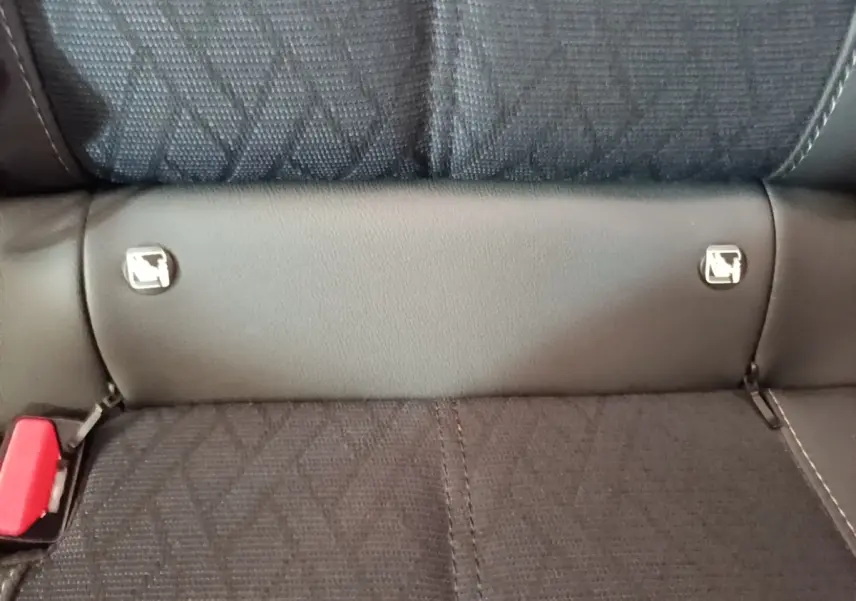 Gros plan sur la banquette arrière noire de l'Opel Corsa avec fixation Isofix et ceinture rouge visible à gauche.