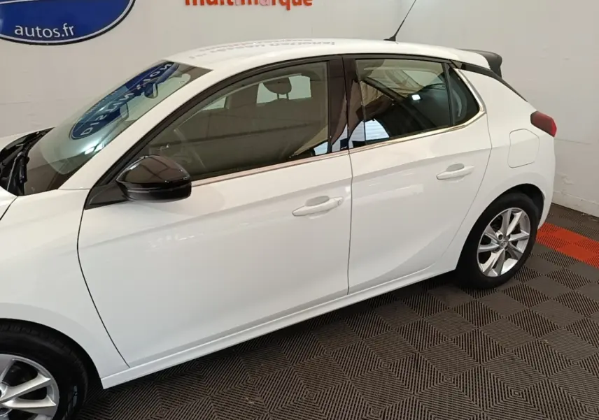 Opel Corsa blanc vue de profil côté gauche, avec rétroviseurs noirs et jantes alliage visibles.