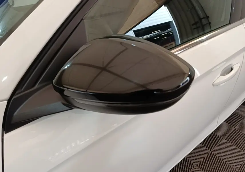 Gros plan sur le rétroviseur noir côté conducteur d'une Opel Corsa blanche vue de profil gauche.