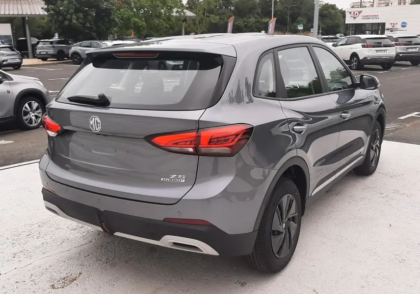 Vue 3/4 arrière droite d'un MG ZS Camden Grey hybride essence 2026 avec feux arrière LED et jantes noires.