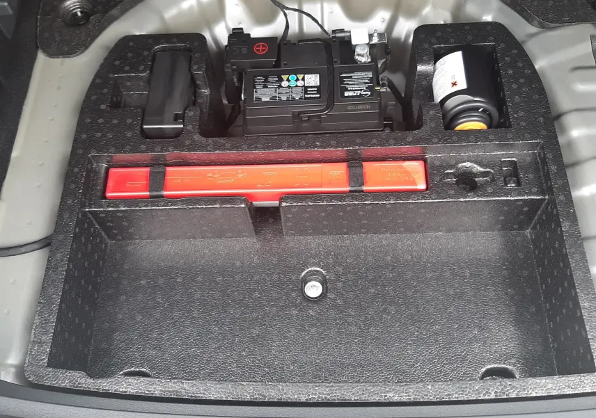 Vue rapprochée du compartiment de rangement sous le coffre du MG Motor ZS Camden Grey 2026, montrant batterie et kit de sécurité.
