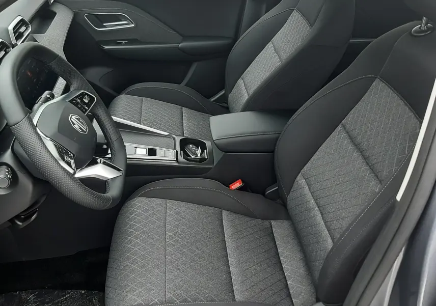 Vue intérieure côté conducteur du MG ZS 1.5 Hybrid+ 2026 en Camden Grey, sièges tissu gris avec surpiqûres et volant multifonction.