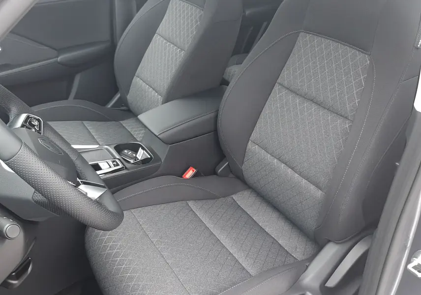 Vue intérieure côté conducteur du MG MOTOR ZS 1.5 HYBRID+ 2026, sièges tissu noir avec motifs losanges.