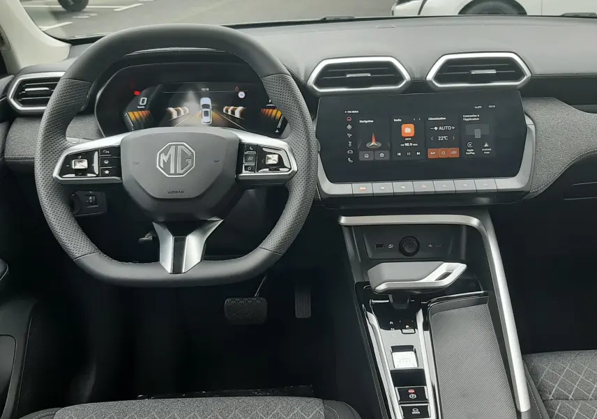 Vue intérieure avant du MG ZS 1.5 Hybrid+ 2026, volant multifonction, écran tactile central et sièges tissu gris.