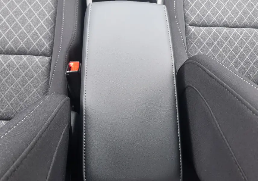 Vue plongeante sur l'accoudoir central en cuir noir entre les sièges tissu gris à motifs du MG ZS 1.5 Hybrid+ 2026.