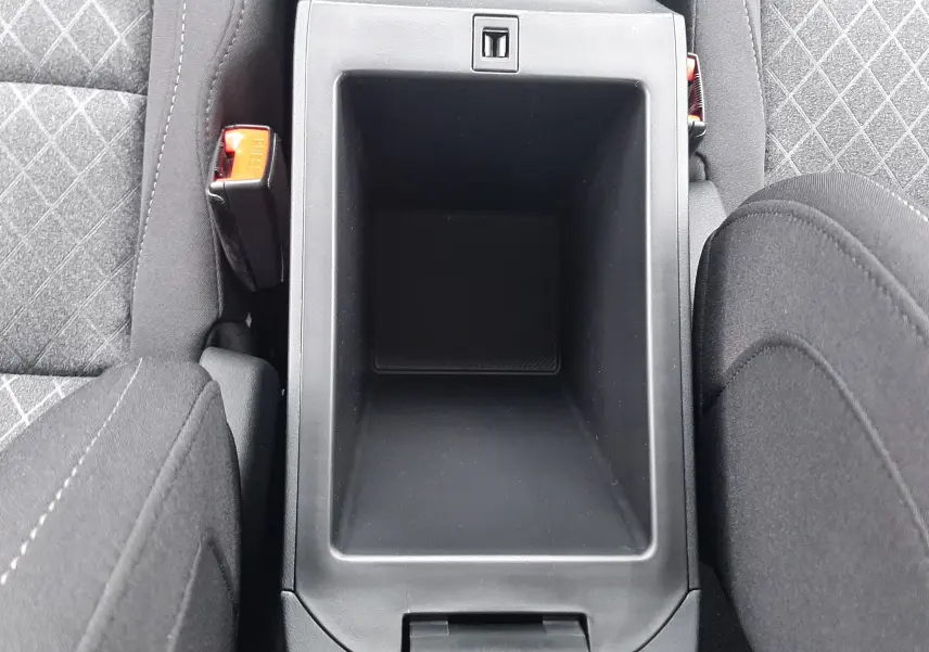 Vue plongeante sur le rangement central noir entre les sièges avant en tissu gris à motifs du MG MOTOR ZS hybride 2026.