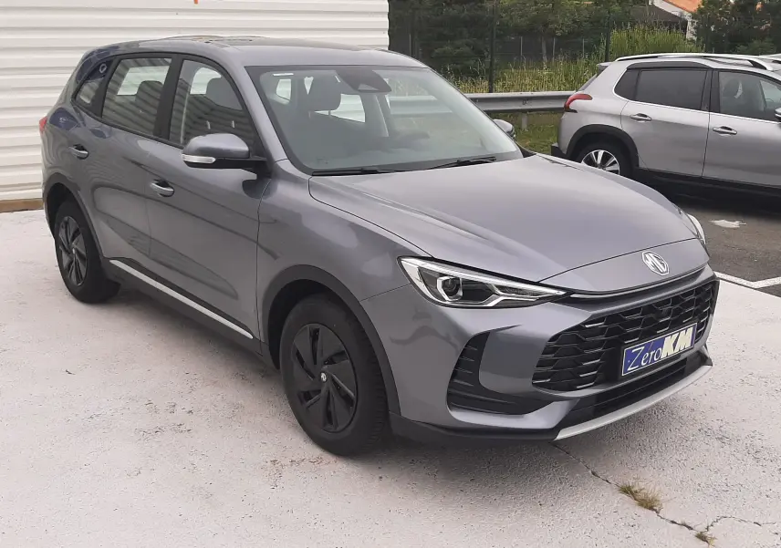 MG ZS 1.5 Hybrid+ gris Camden, vue 3/4 avant droit, avec calandre large et phares LED distinctifs.