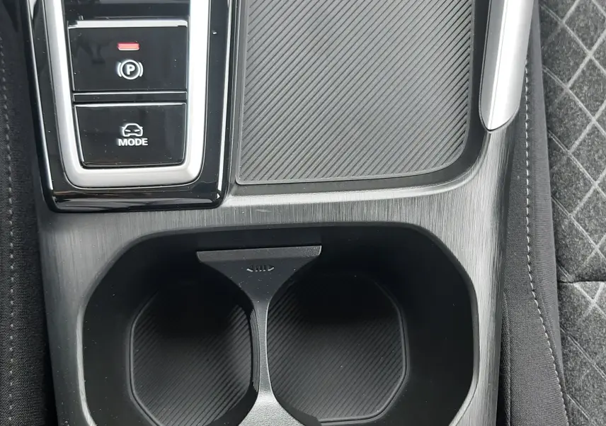 Gros plan sur la console centrale noire du MG ZS 1.5 Hybrid+ 2026, montrant porte-gobelets et commandes de mode de conduite.