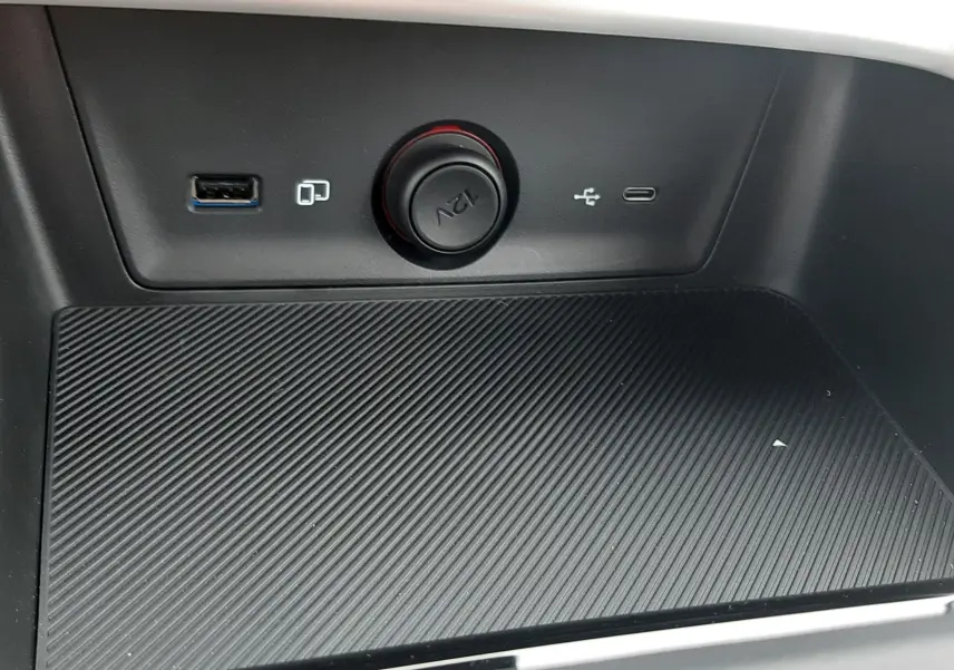 Gros plan sur la console centrale du MG ZS 1.5 Hybrid+ 2026, montrant les ports USB, prise 12V et surface antidérapante noire.