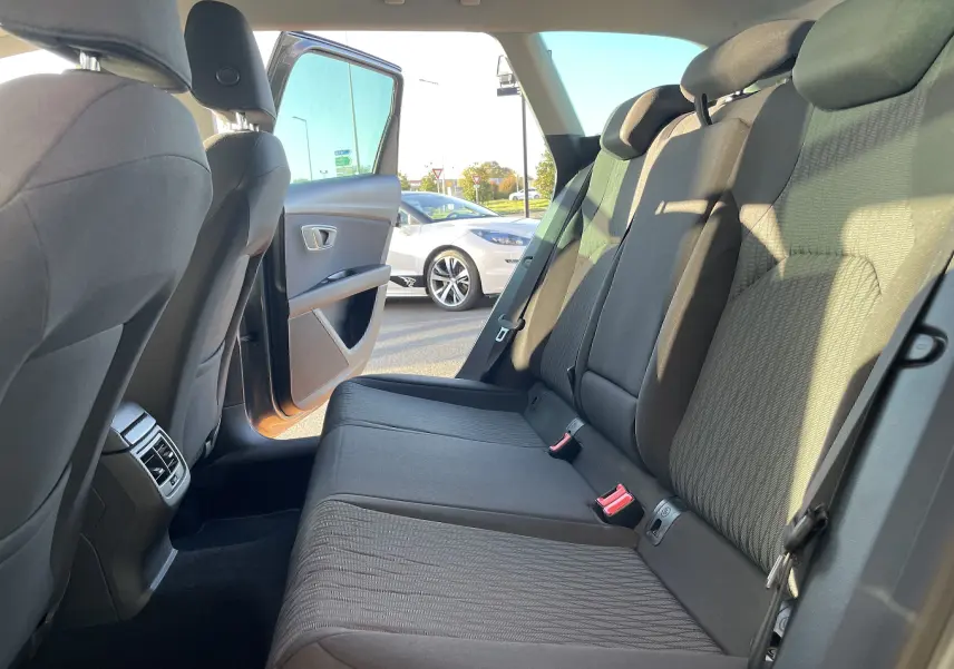 Vue intérieure arrière côté droit de la SEAT LEON ST 1.2 TSI gris, sièges tissu gris-noir et porte arrière ouverte.