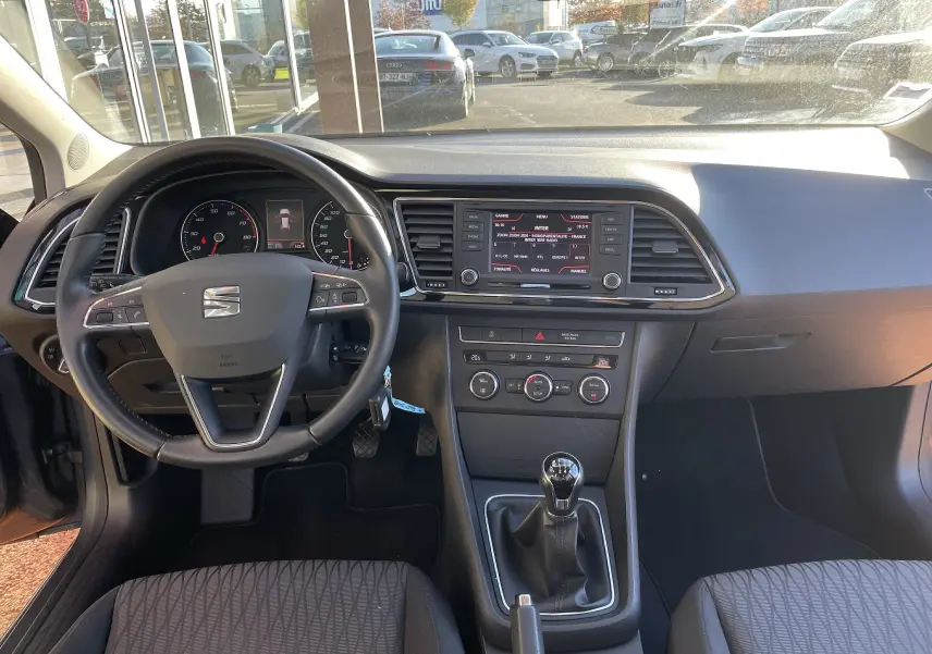 Intérieur gris noir de la SEAT LEON ST 1.2 TSI 2013, vue du tableau de bord avec volant, écran GPS et boîte manuelle.