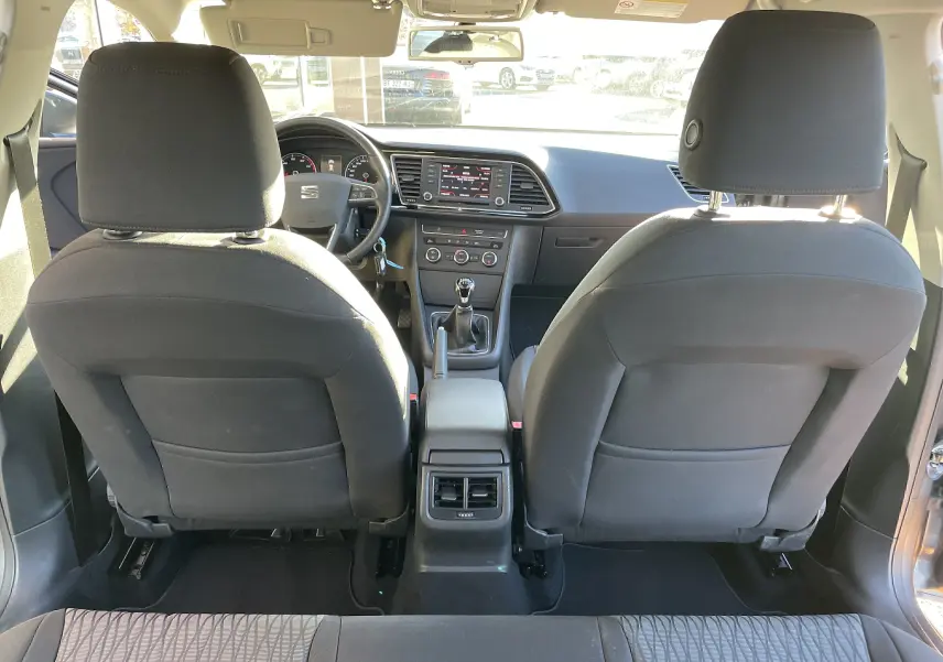 Vue intérieure arrière d'une SEAT LEON ST gris 2013, montrant les sièges avant en tissu noir et la console centrale avec boîte manuelle.