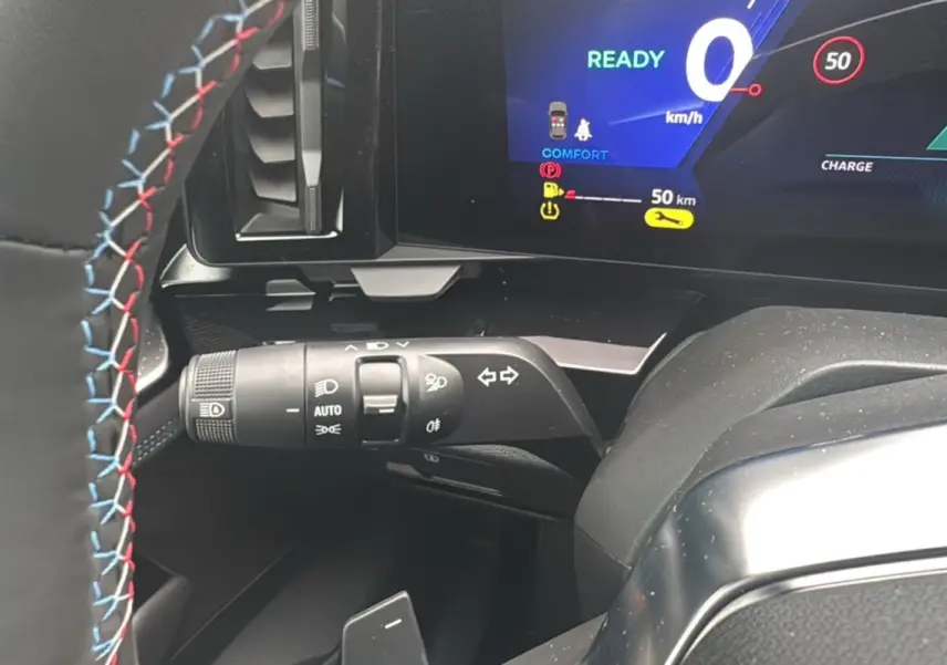 Gros plan sur le commodo gauche et le tableau de bord digital du Renault Austral E-Tech 200 gris schiste avec volant surpiqué tricolore.