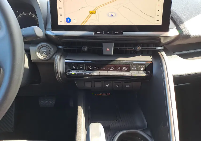 Vue intérieure du tableau de bord du Toyota C-HR gris minéral 2025, avec écran tactile de navigation et commandes climatisation.