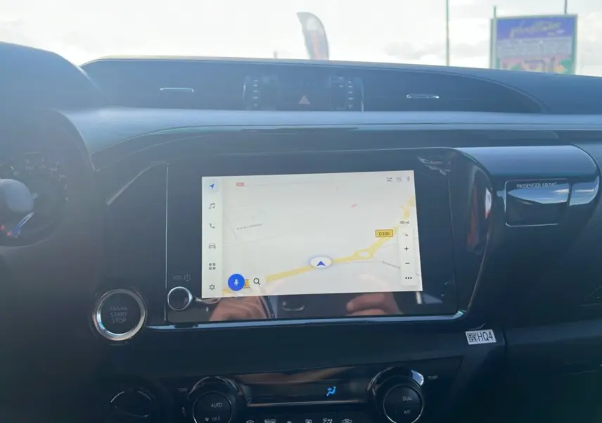 Tableau de bord du Toyota Hilux 2025 avec écran tactile GPS et bouton start/stop, finition Invincible gris atlas.