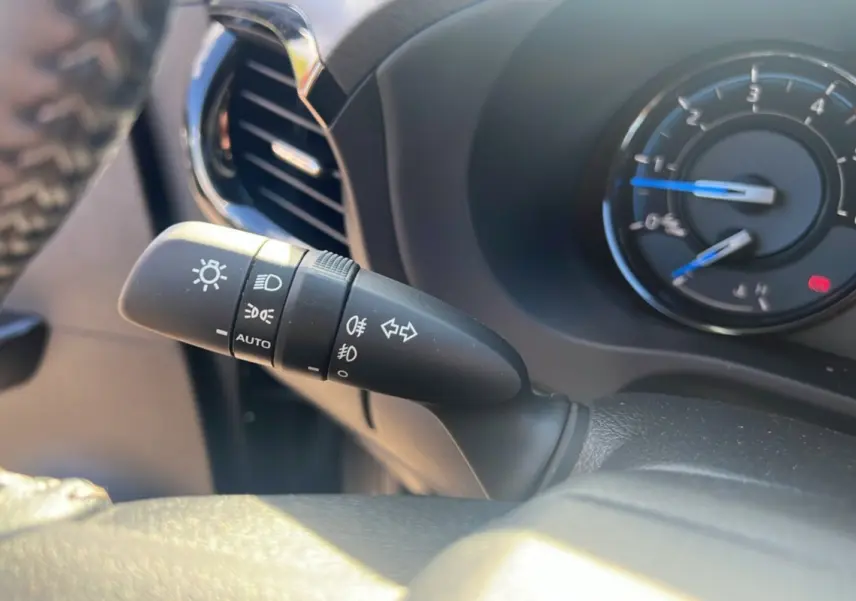 Gros plan sur la manette des feux et clignotants du Toyota Hilux 4x4 gris atlas, tableau de bord en arrière-plan.