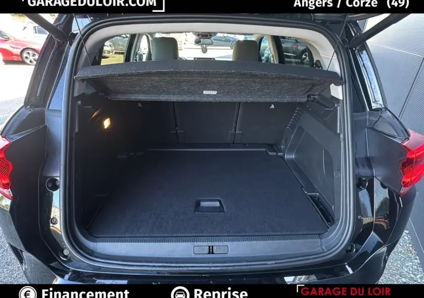 Coffre ouvert vu de l'arrière d'un Citroën C5 Aircross noir 2025, avec tablette cache-bagages et intérieur spacieux.
