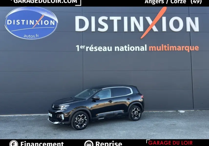 Vue de profil droit d'un Citroën C5 Aircross noir 2025 garé devant un mur gris avec logo Distinxion.