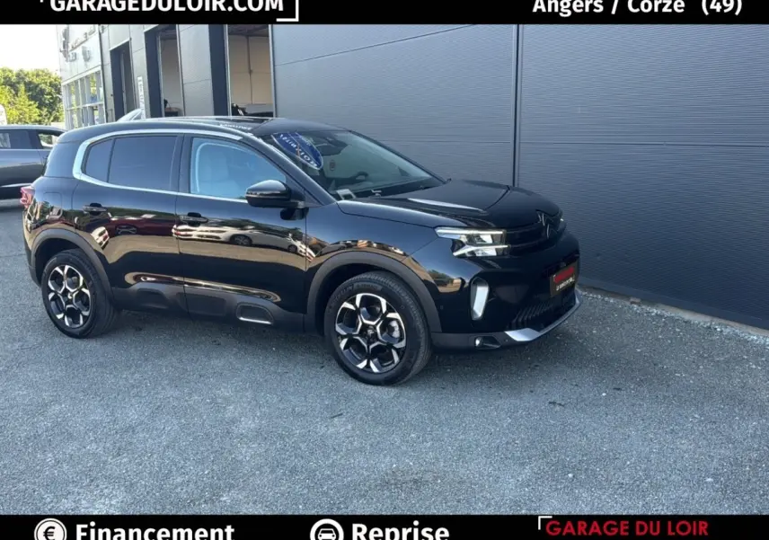 Vue 3/4 avant droite d'un Citroën C5 Aircross noir 2025 avec jantes distinctives et protections latérales noires.